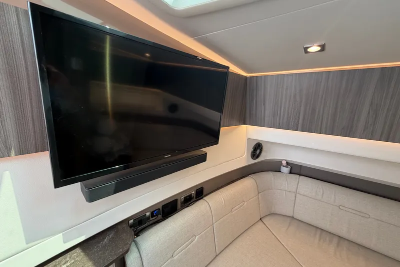 Slide: The Image of 2023 Sea Ray SLX 400 interior with TV, modern seating, and ambient lighting. - 38