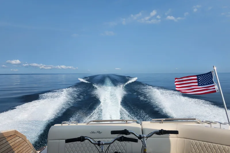Slide: The Image of 2023 Sea Ray SLX 400 cruising with American flag, leaving a wake on calm water. - 41