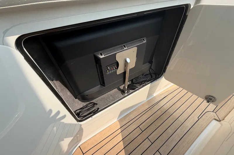 Slide: The Image of Storage compartment with TV on 2023 Sea Ray SLX 400 boat, featuring teak flooring. - 17