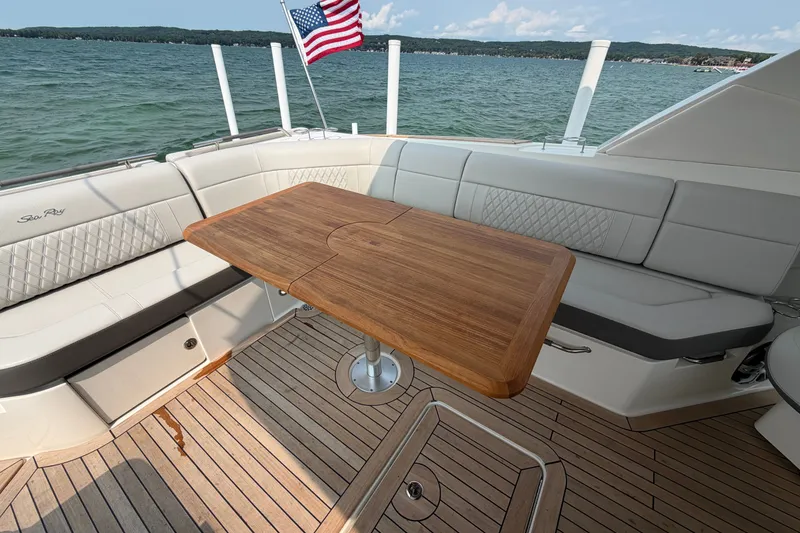 Slide: The Image of 2023 Sea Ray SLX 400 boat interior with wooden table and seating, overlooking a scenic lake. - 28