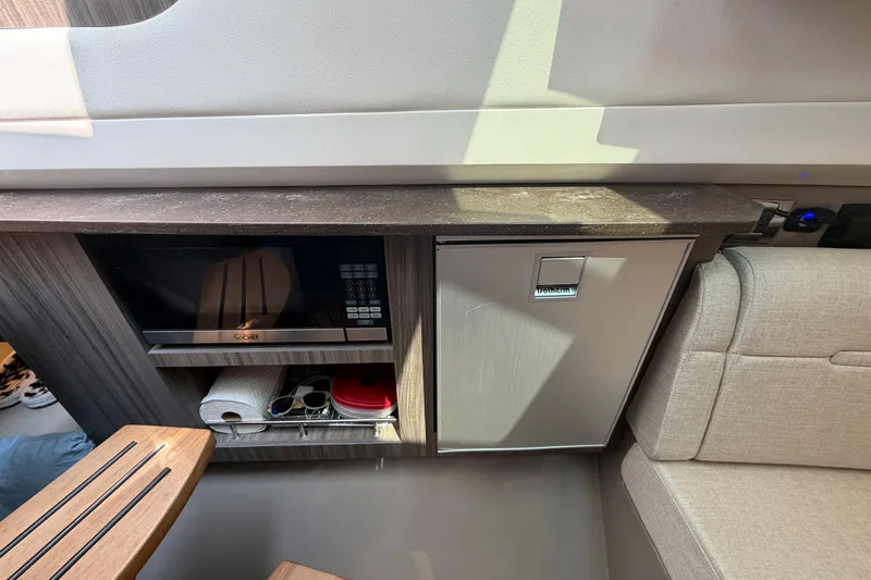 Slide: The Image of 2023 Sea Ray SLX 400 interior with microwave, mini fridge, and seating area. - 37