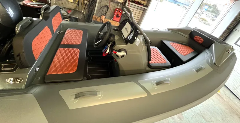 The Image of The image shows a 2023 Highfield Sport 360 boat with red upholstery and a modern helm. - 0