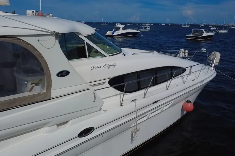 Slide: The Image of 2003 Sea Ray 480 Motor Yacht docked on calm waters, surrounded by other boats. - 210