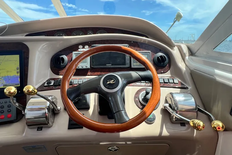 Slide: The Image of 2003 Sea Ray 480 Motor Yacht helm with wooden steering wheel and navigation controls. - 89