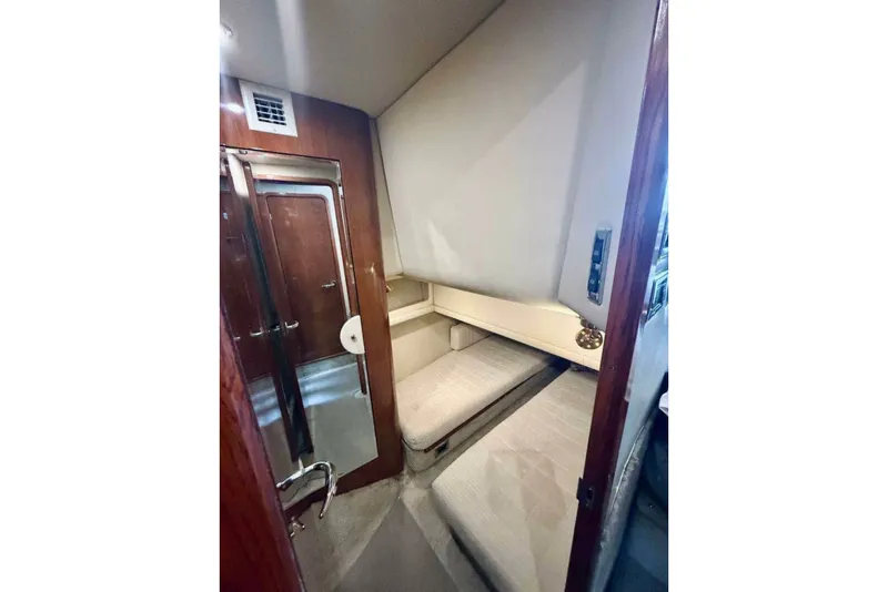 Slide: The Image of 2003 Sea Ray 480 Motor Yacht interior cabin with cozy sleeping area and wooden accents. - 14