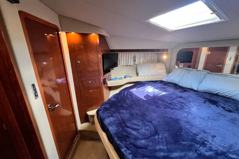 Slide: The Image of Luxurious 2003 Sea Ray 480 Motor Yacht bedroom with plush bedding and elegant wood cabinetry. - 107