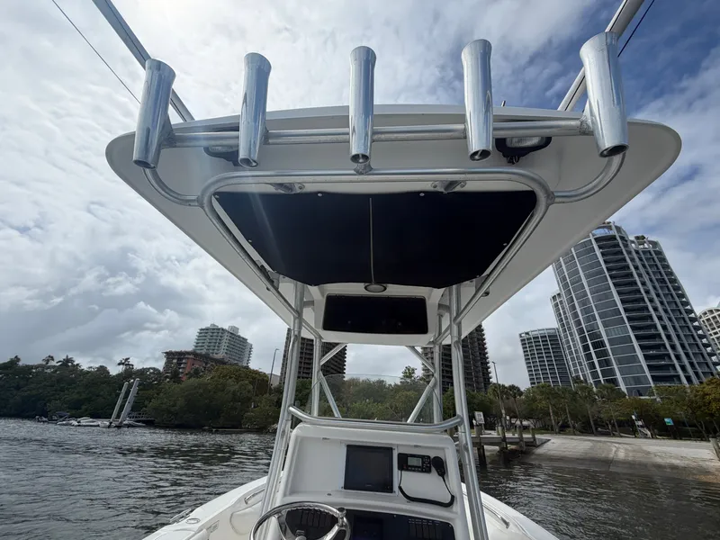 Slide: The Image of A 2006 Boston Whaler 240 Outrage with T-top and rod holders, set against an urban skyline. - 13