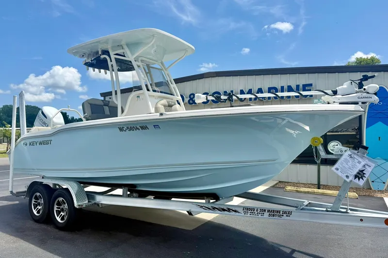 The Image of 2025 Key West 219 FS boat on trailer at marine dealership, sunny day. - 1