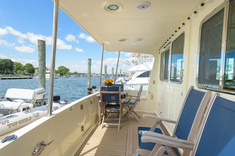 Slide: The Image of 2017 North Pacific 49 Pilothouse yacht deck with seating, overlooking serene waterfront. - 51
