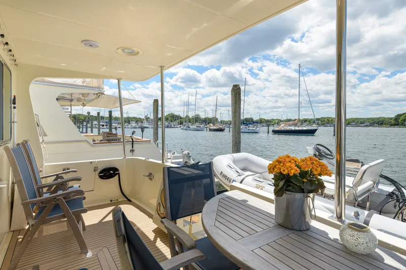 Slide: The Image of Luxurious 2017 North Pacific 49 Pilothouse yacht deck with seating, table, and scenic marina view. - 54