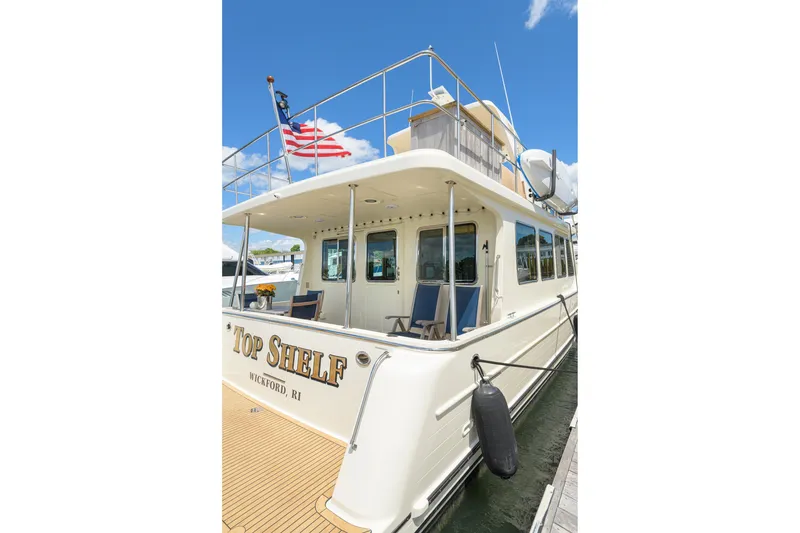 Slide: The Image of 2017 North Pacific 49 Pilothouse yacht docked, featuring "Top Shelf" name and American flag. - 50