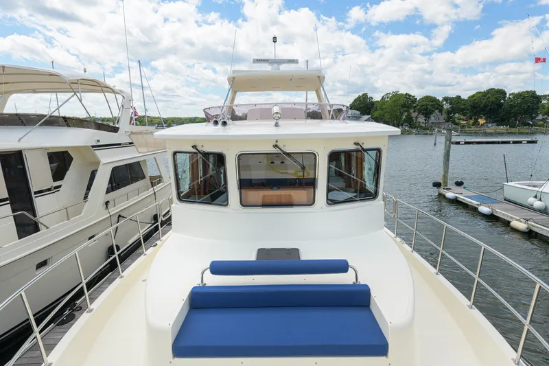 Slide: The Image of 2017 North Pacific 49 Pilothouse yacht docked, featuring spacious deck and blue seating. - 72