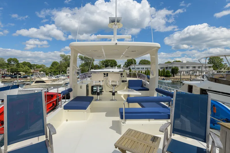Slide: The Image of 2017 North Pacific 49 Pilothouse yacht deck with seating, marina view, and blue skies. - 63