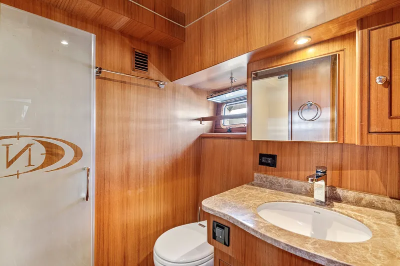 Slide: The Image of Luxurious bathroom in 2017 North Pacific 49 Pilothouse yacht with wood paneling and marble countertop. - 27