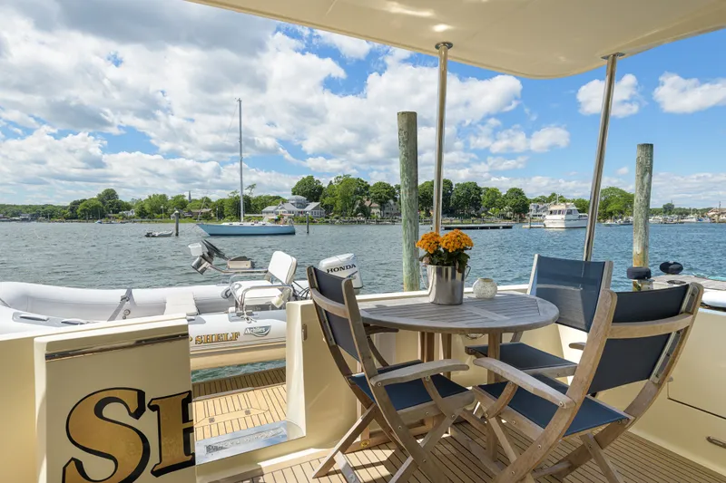 Slide: The Image of 2017 North Pacific 49 Pilothouse yacht deck with table, chairs, and scenic waterfront view. - 53