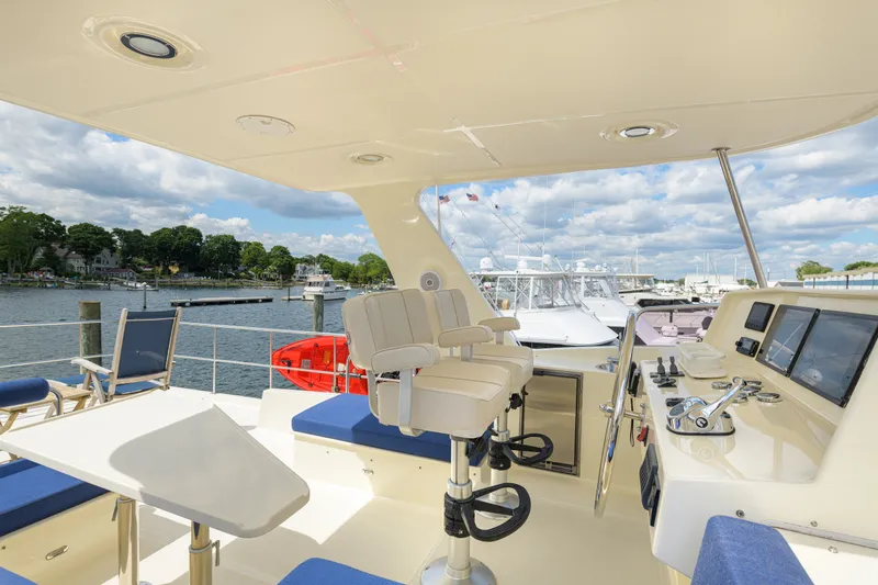 Slide: The Image of 2017 North Pacific 49 Pilothouse yacht helm with seating, overlooking marina. - 57