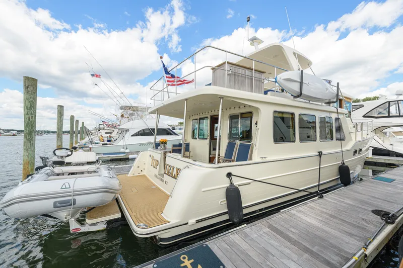 Slide: The Image of 2017 North Pacific 49 Pilothouse yacht docked with inflatable boat, clear sky background. - 1