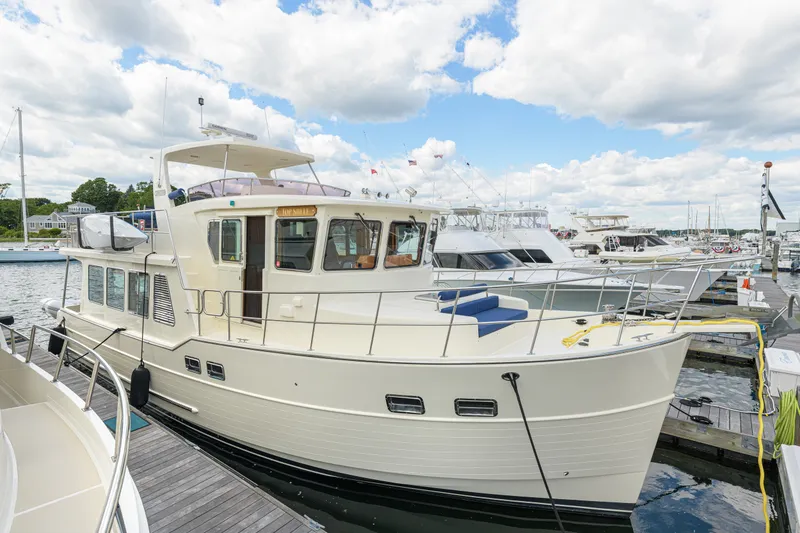 Slide: The Image of 2017 North Pacific 49 Pilothouse yacht docked at a marina under a partly cloudy sky. - 44