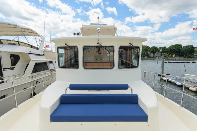Slide: The Image of 2017 North Pacific 49 Pilothouse yacht with blue seating, docked by the water. - 71