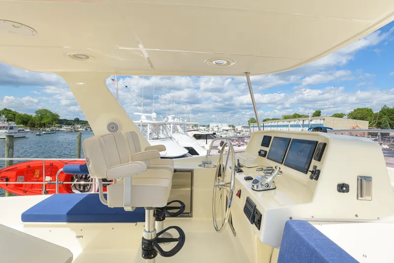 Slide: The Image of Pilothouse of 2017 North Pacific 49 yacht with helm, controls, and marina view. - 56