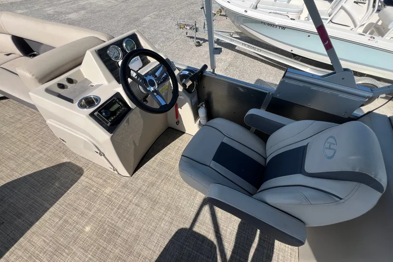 Slide: The Image of 2023 Harris Cruiser 230 boat interior with steering wheel and captain's chair. - 7
