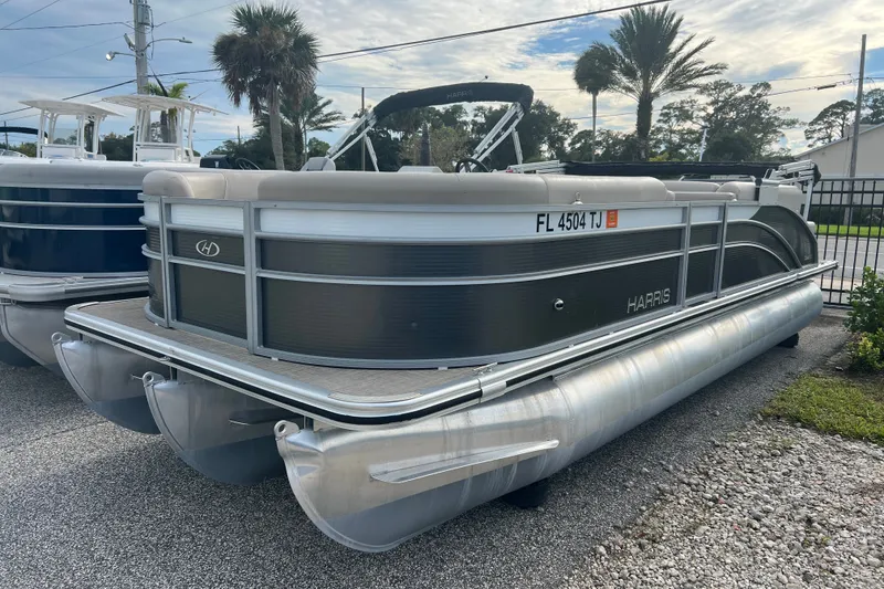 The Image of 2023 Harris Cruiser 230 pontoon boat parked outdoors with palm trees in the background. - 0