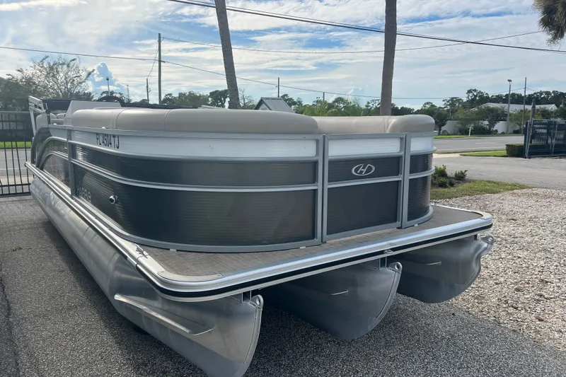 Slide: The Image of 2023 Harris Cruiser 230 pontoon boat parked on gravel lot. - 2