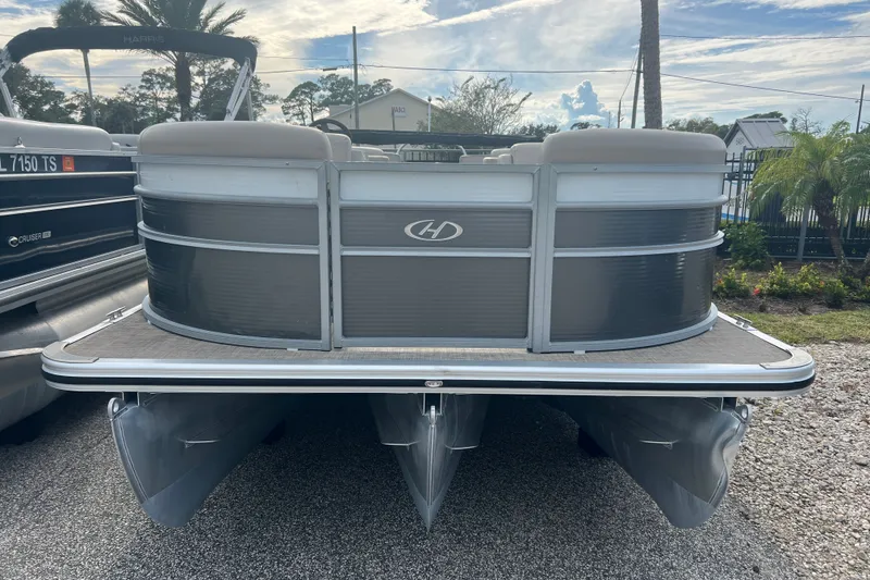 Slide: The Image of 2023 Harris Cruiser 230 pontoon boat, front view, parked on gravel. - 1