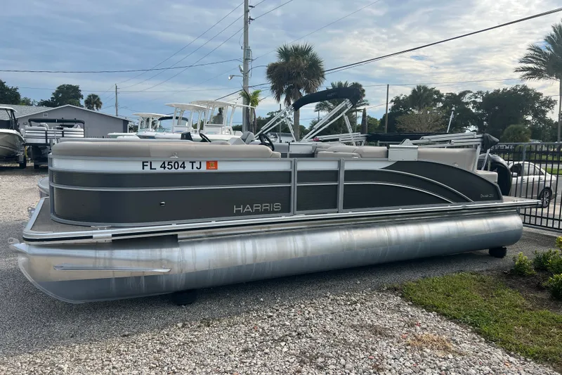 Slide: The Image of 2023 Harris Cruiser 230 pontoon boat parked on gravel lot. - 3