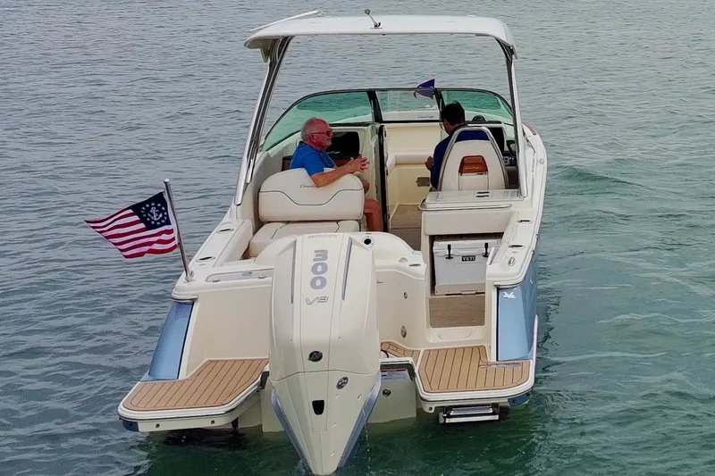 Slide: The Image of 2024 Chris-Craft Calypso 24 boat cruising on water with passengers and American flag. - 13