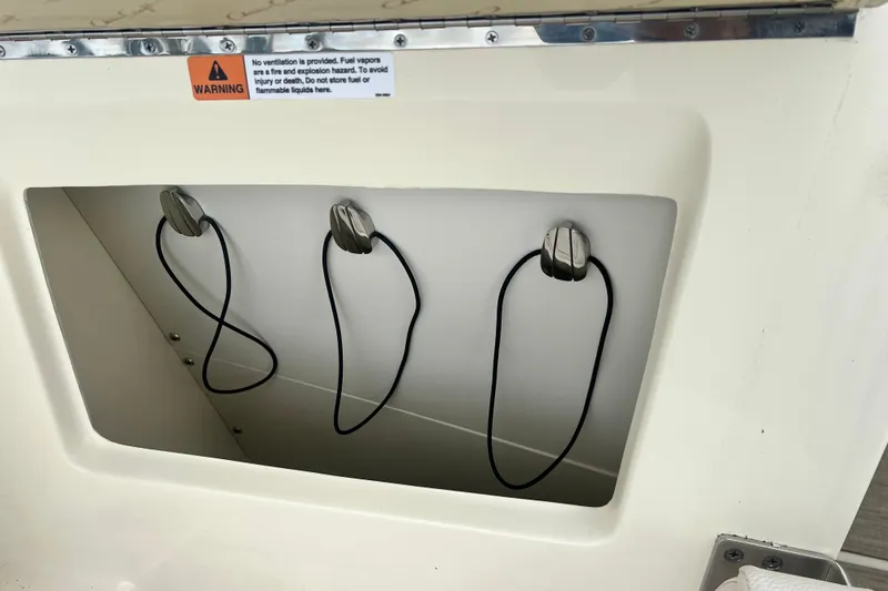 Slide: The Image of 2024 Chris-Craft Calypso 24 storage compartment with warning label and cables. - 29