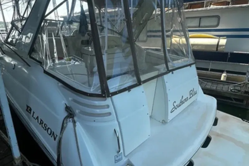 Slide: The Image of 2004 Larson Cabrio 330 boat docked, featuring a sleek design and clear canopy. - 2