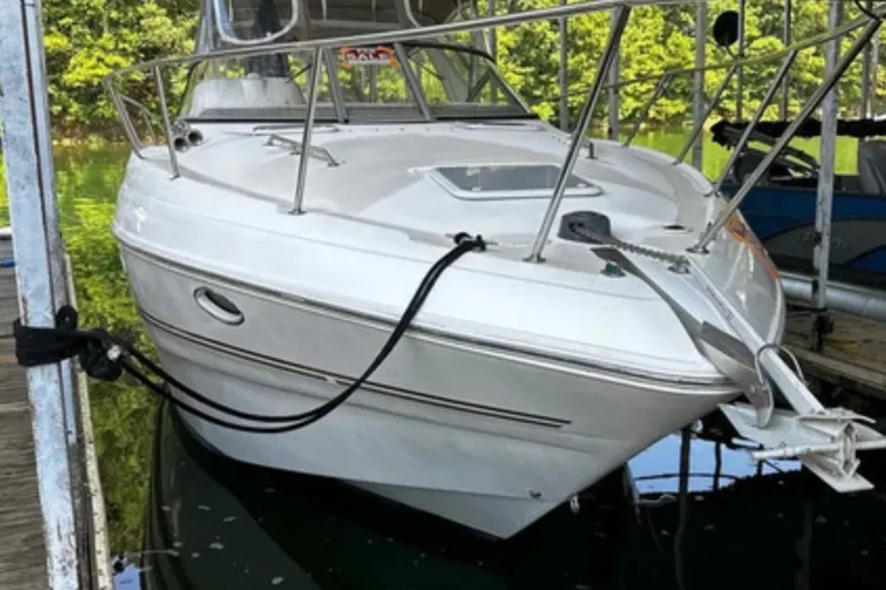 Slide: The Image of 2004 Larson Cabrio 330 boat docked on calm water, surrounded by greenery. - 1