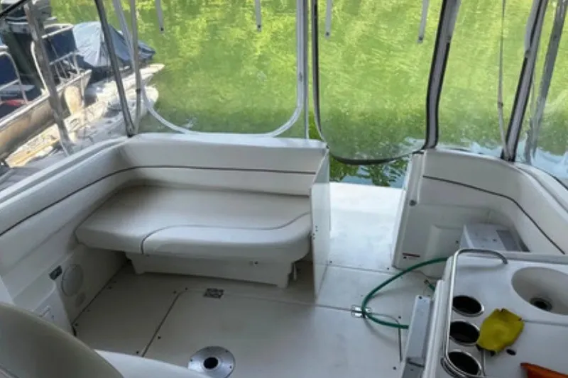 Slide: The Image of Interior of a 2004 Larson Cabrio 330 boat with white seating and a small kitchenette. - 9