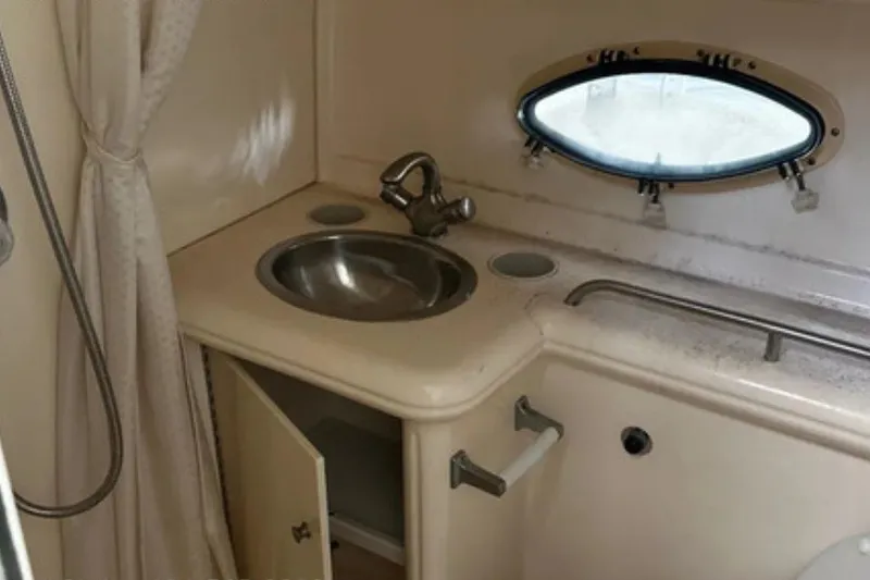 Slide: The Image of 2004 Larson Cabrio 330 boat bathroom with sink, porthole, and shower curtain. - 8