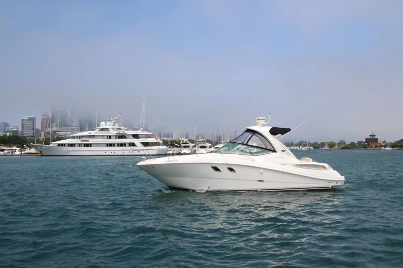 The Image of 2012 Sea Ray 330 Sundancer yacht on water with cityscape background. - 0