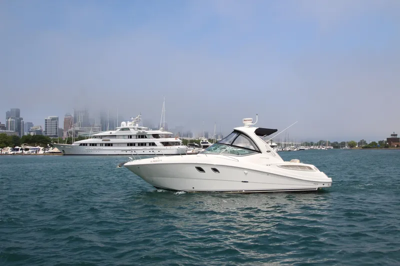 Slide: The Image of 2012 Sea Ray 330 Sundancer yacht on water with city skyline in background. - 1