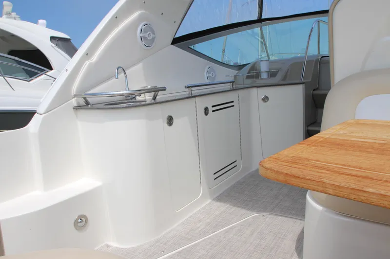 Slide: The Image of Interior of 2012 Sea Ray 330 Sundancer boat with white cabinetry and wooden table. - 11