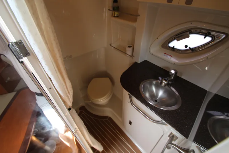 Slide: The Image of 2012 Sea Ray 330 Sundancer bathroom with sink, toilet, and porthole window. - 42