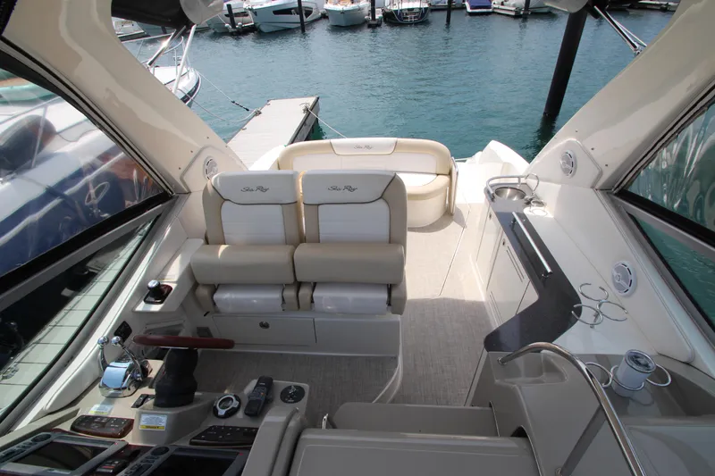 Slide: The Image of 2012 Sea Ray 330 Sundancer cockpit with helm, seating, and marina view. - 19