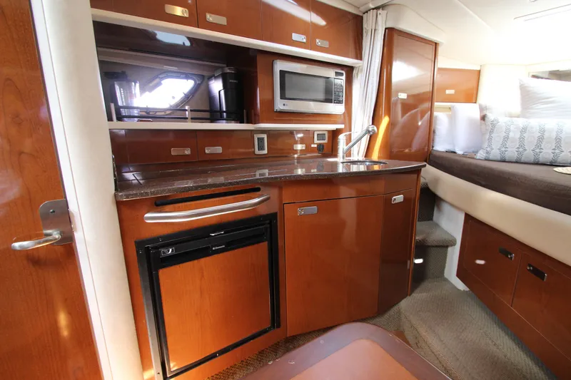 Slide: The Image of 2012 Sea Ray 330 Sundancer interior kitchen with microwave, sink, and mini-fridge. - 32