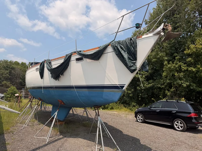 Slide: The Image of A 1991 Sabre 425 sailboat is on a dry dock next to a black car. - 1