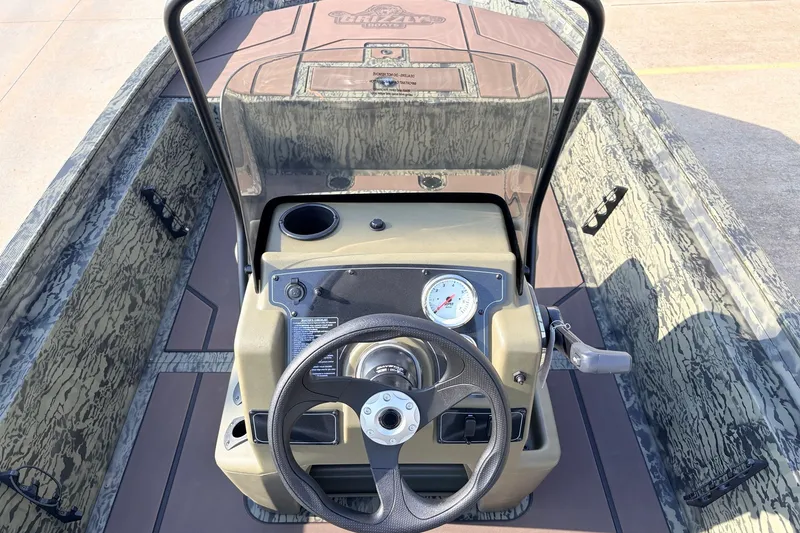 Slide: The Image of 2027 Tracker Grizzly 1860 CC boat interior with steering console and camouflage design. - 21
