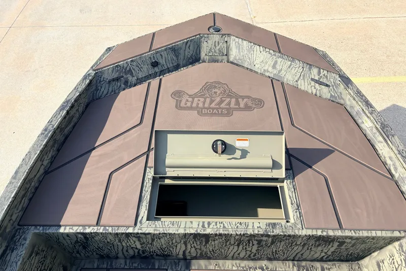 Slide: The Image of 2027 Tracker Grizzly 1860 CC boat deck with storage compartment, camo design. - 14