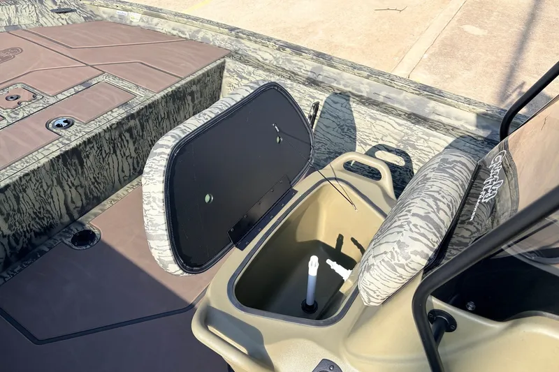 Slide: The Image of 2027 Tracker Grizzly 1860 CC boat interior with open storage compartment and camouflage seating. - 19