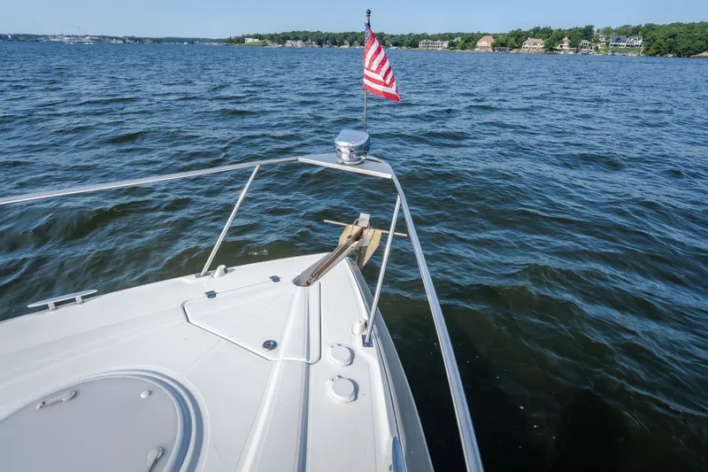 Slide: The Image of 2012 Cruisers Yachts 380 Express on water with American flag, scenic shoreline view. - 62