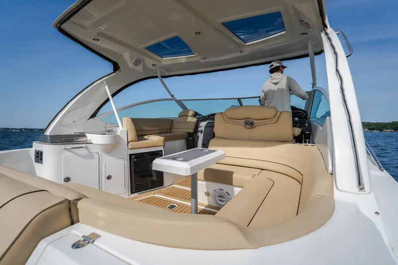 Slide: The Image of 2012 Cruisers Yachts 380 Express interior with beige seating and modern helm on open water. - 21