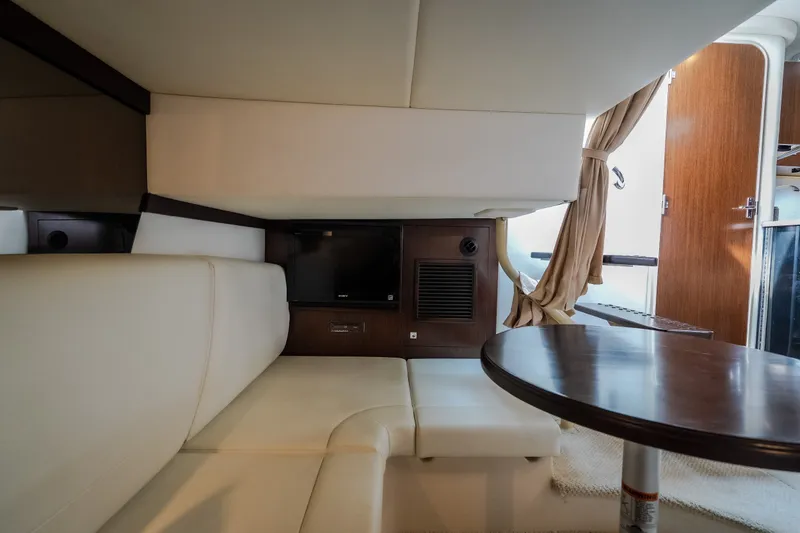 Slide: The Image of Interior of 2012 Cruisers Yachts 380 Express, featuring a cozy seating area and wooden table. - 45