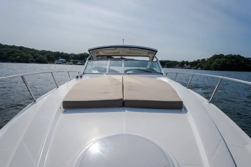 Slide: The Image of 2012 Cruisers Yachts 380 Express on a serene lake, featuring a spacious sun deck. - 64