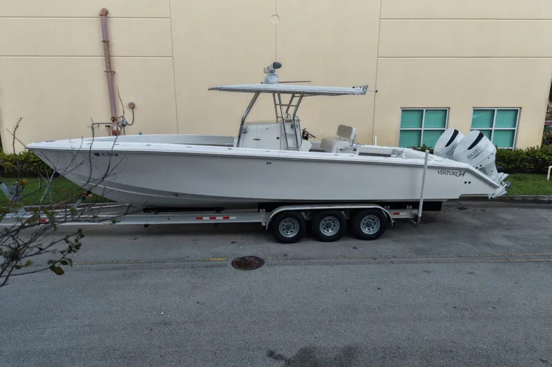 Slide: The Image of 1997 Venture 34 Center Console boat on a trailer, parked beside a building. - 3